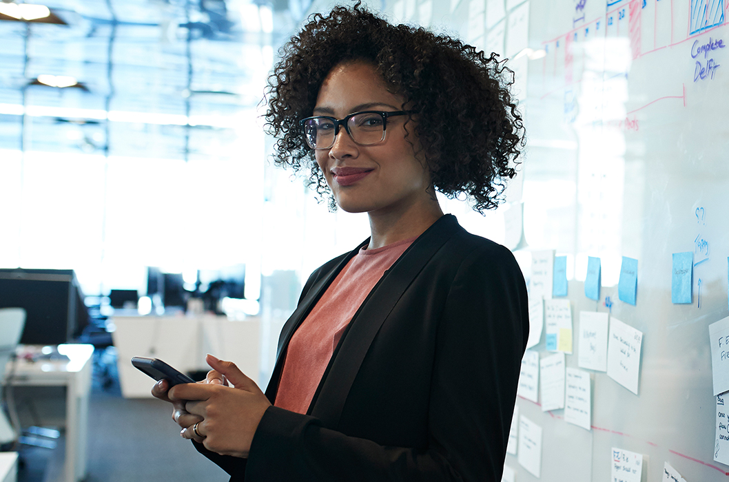 Young woman wearing glasses and standing in front of a planning board